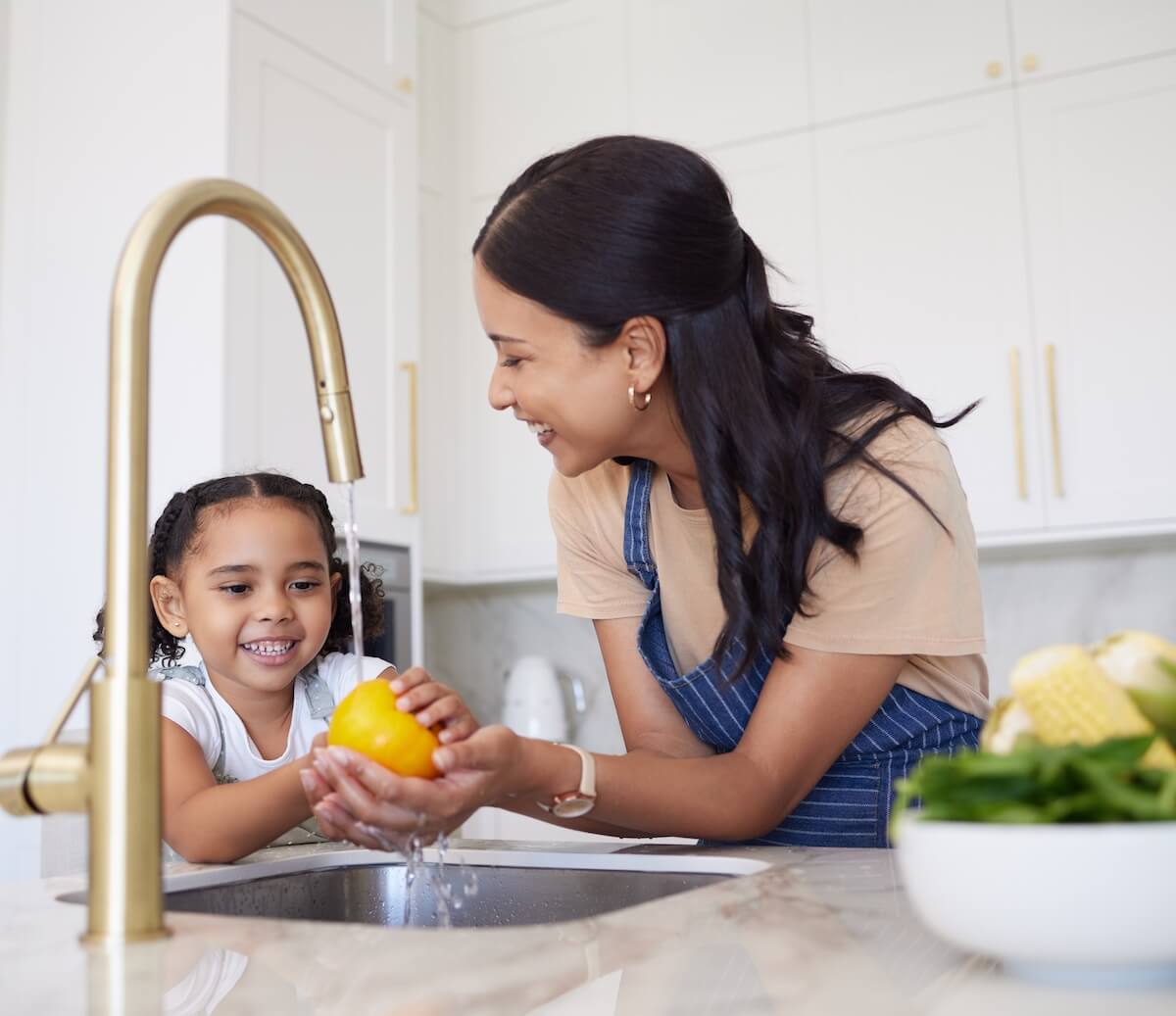 Mother and daughter wash a lemon in a new kitchen plumbing installation.